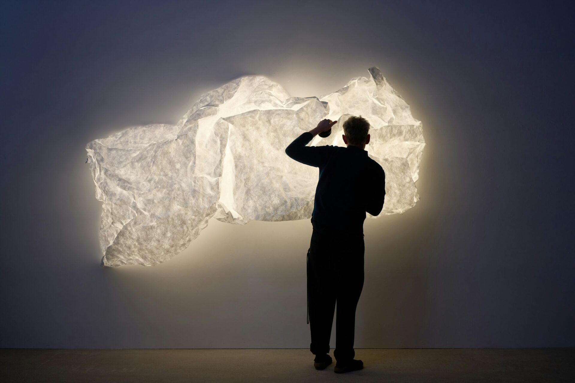 Siluetă privind o instalație luminoasă pe perete