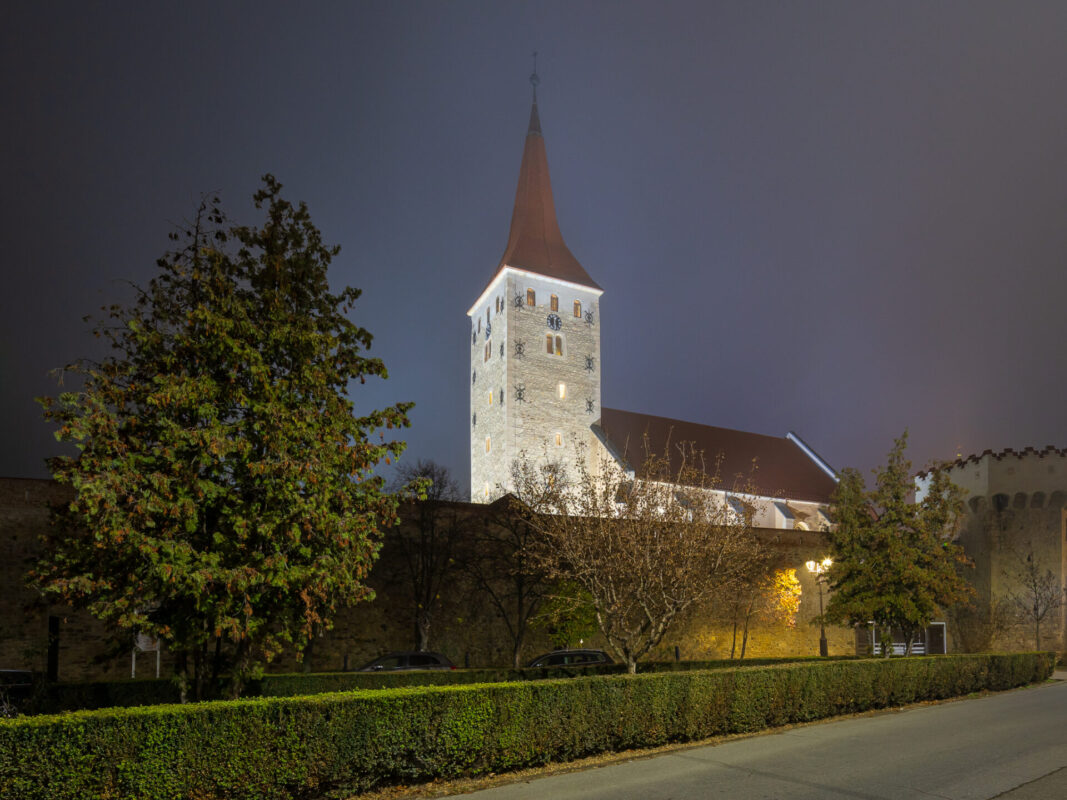 Turn medieval iluminat noaptea lângă ziduri fortificate